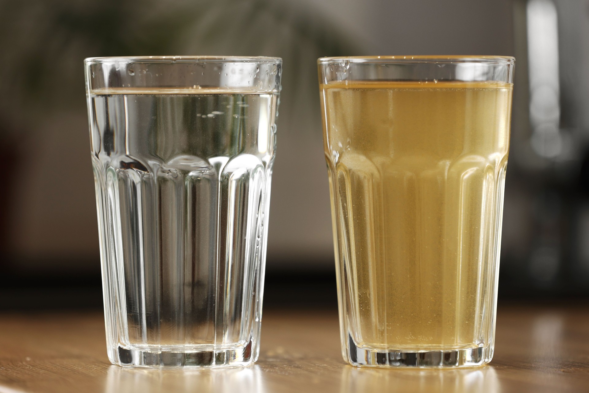 House water filtration system to drinkable condition. Glass of clear water after reverse osmos filtration and glass of dirty water on tabletop on kitchen. Evidence of contamination of tap water
